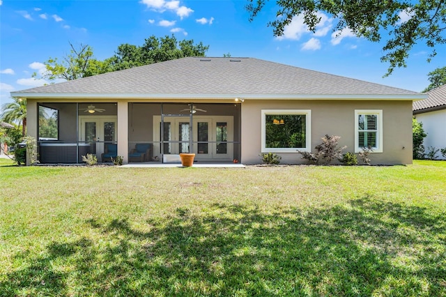 rear view of house with a yard, ceiling fan, a hot tub, stucco siding, and french doors
