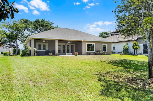 back of house with ceiling fan, stucco siding, a sunroom, and a lawn