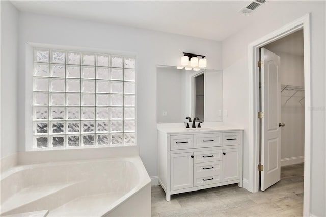 542 Terrace Cove Way, Orlando, FL 32828 - bathroom featuring wood finished floors, visible vents, vanity, a walk in closet, and a bath