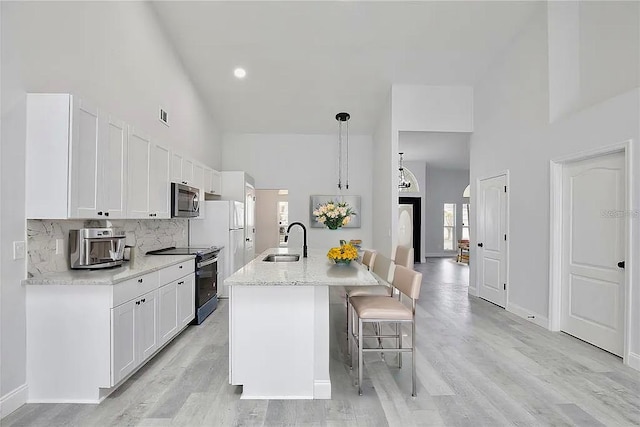 542 Terrace Cove Way, Orlando, FL 32828 - kitchen with a sink, stainless steel microwave, white cabinetry, high vaulted ceiling, and electric stove