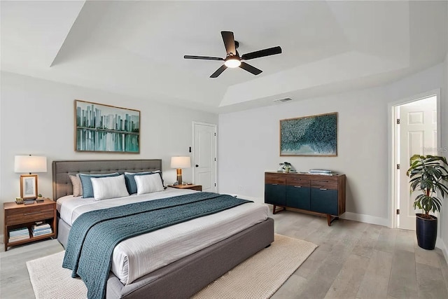 542 Terrace Cove Way, Orlando, FL 32828 - bedroom with ceiling fan, a tray ceiling, light wood finished floors, baseboards, and visible vents
