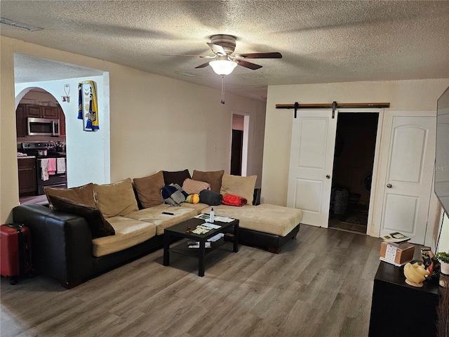 509 S Hudson St, Orlando, FL 32835 - living room with a textured ceiling, a barn door, visible vents, ceiling fan, and wood finished floors