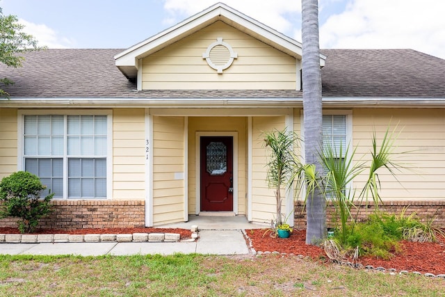 entrance to property with brick siding and a shingled roof