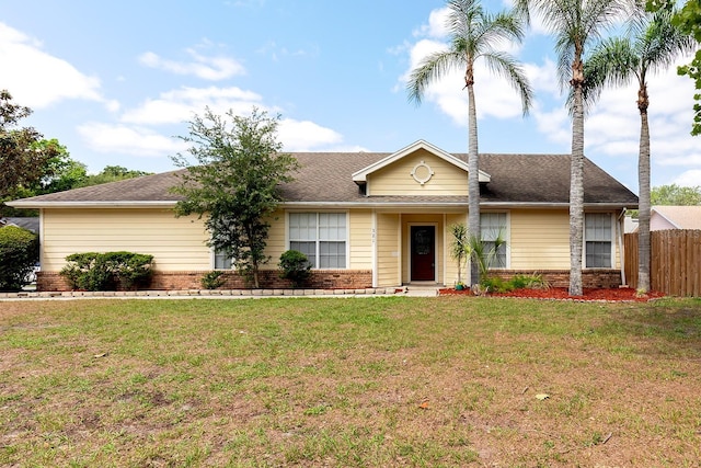 ranch-style house featuring fence, roof with shingles, a front lawn, and brick siding