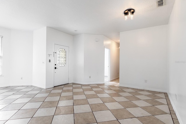 empty room featuring baseboards, light tile patterned flooring, and visible vents