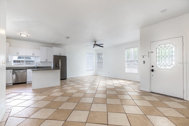 kitchen with a ceiling fan, dark countertops, white cabinetry, a sink, and stainless steel appliances