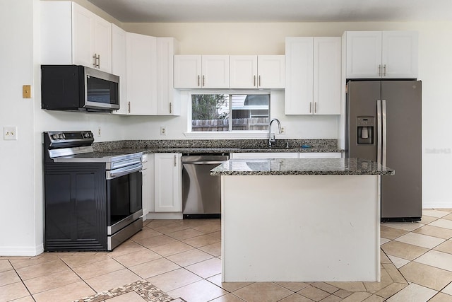kitchen with a kitchen island, a sink, white cabinets, dark stone countertops, and stainless steel appliances