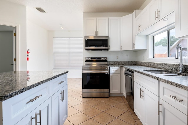 kitchen featuring a sink, white cabinets, light tile patterned flooring, and stainless steel appliances