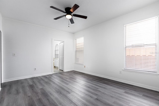 unfurnished bedroom with baseboards, ceiling fan, dark wood-style floors, and connected bathroom