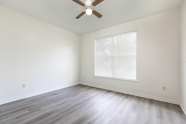 spare room featuring baseboards, ceiling fan, and wood finished floors