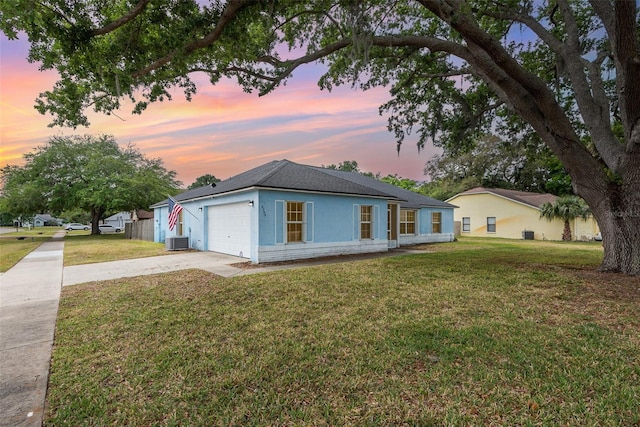ranch-style home with central air condition unit, a garage, concrete driveway, stucco siding, and a lawn