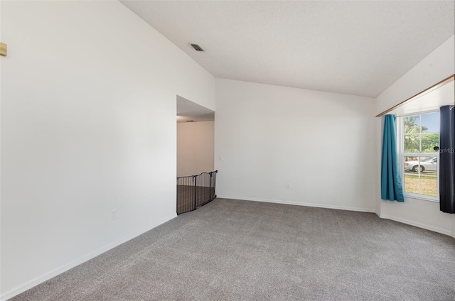 carpeted spare room featuring baseboards, lofted ceiling, and visible vents