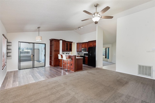 kitchen with visible vents, a breakfast bar area, black appliances, and open floor plan