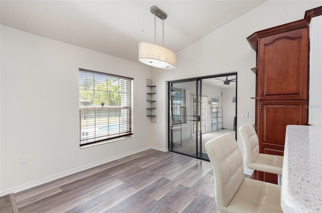 unfurnished dining area with baseboards, vaulted ceiling, and light wood-type flooring