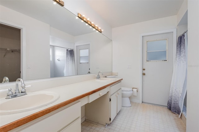 full bathroom with double vanity, a sink, tile patterned floors, and toilet
