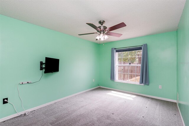 carpeted empty room featuring baseboards, a textured ceiling, and a ceiling fan