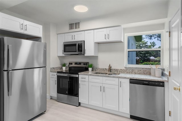 239 S Lake Cortez Dr, Apopka, FL 32703 - kitchen with appliances with stainless steel finishes, a sink, white cabinetry, light stone countertops, and light wood-style flooring
