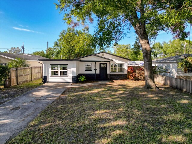 1121 49th Ave N, Saint Petersburg, FL 33703 - view of front of home with driveway, fence, a front yard, and stucco siding
