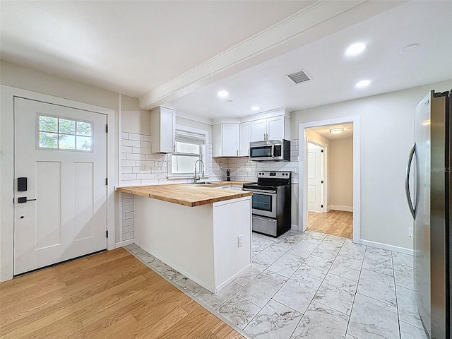 1121 49th Ave N, Saint Petersburg, FL 33703 - kitchen featuring visible vents, a peninsula, stainless steel appliances, butcher block counters, and tasteful backsplash