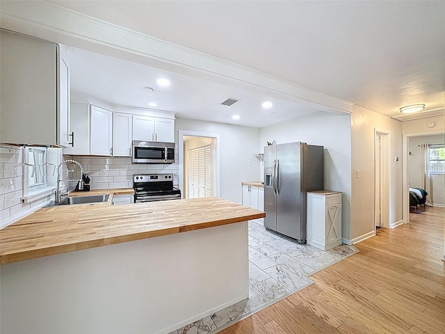 1121 49th Ave N, Saint Petersburg, FL 33703 - kitchen with butcher block counters, a sink, visible vents, a peninsula, and appliances with stainless steel finishes