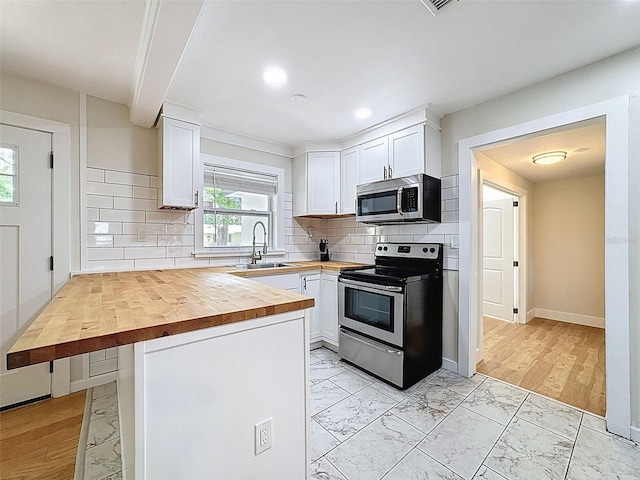 1121 49th Ave N, Saint Petersburg, FL 33703 - kitchen with a sink, wooden counters, stainless steel appliances, marble finish floor, and white cabinets