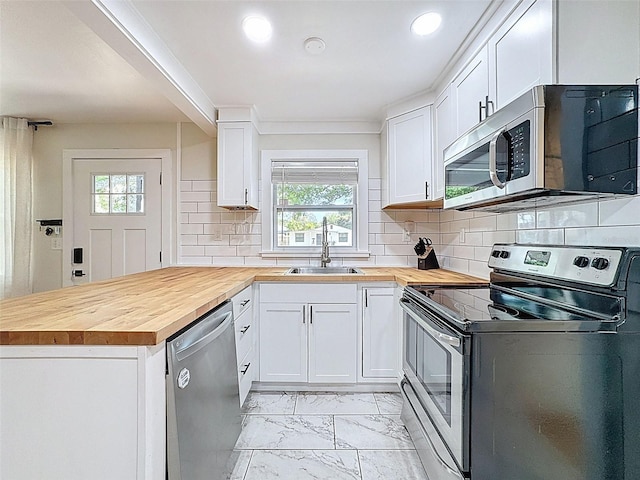 1121 49th Ave N, Saint Petersburg, FL 33703 - kitchen featuring butcher block countertops, a peninsula, marble finish floor, stainless steel appliances, and a sink