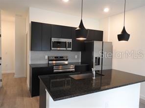 3296 Tranquil Trl, Kissimmee, FL 34747 - kitchen featuring appliances with stainless steel finishes, dark countertops, dark cabinetry, and recessed lighting