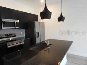 3296 Tranquil Trl, Kissimmee, FL 34747 - kitchen featuring appliances with stainless steel finishes, dark cabinets, dark countertops, backsplash, and baseboards