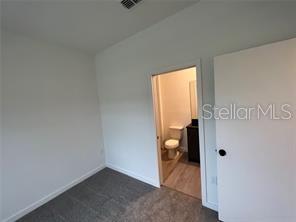 3296 Tranquil Trl, Kissimmee, FL 34747 - unfurnished bedroom featuring dark colored carpet and baseboards
