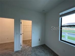 3296 Tranquil Trl, Kissimmee, FL 34747 - unfurnished bedroom with a spacious closet, baseboards, a closet, and carpet