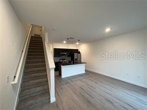 3296 Tranquil Trl, Kissimmee, FL 34747 - unfurnished living room with baseboards, stairway, dark wood-style flooring, and recessed lighting