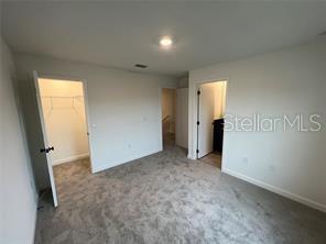 3296 Tranquil Trl, Kissimmee, FL 34747 - unfurnished bedroom with a walk in closet, carpet floors, a closet, baseboards, and recessed lighting