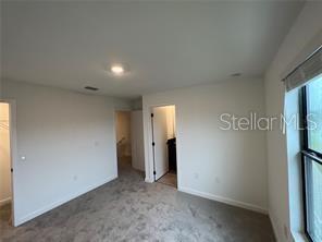 3296 Tranquil Trl, Kissimmee, FL 34747 - unfurnished bedroom featuring a spacious closet, baseboards, and carpet