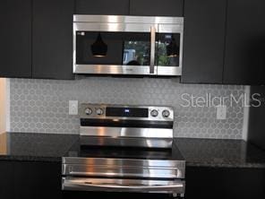 3296 Tranquil Trl, Kissimmee, FL 34747 - kitchen with stainless steel appliances, dark cabinetry, modern cabinets, and tasteful backsplash