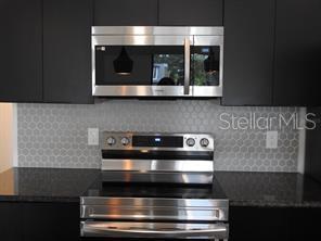3296 Tranquil Trl, Kissimmee, FL 34747 - kitchen featuring stainless steel appliances, dark cabinets, dark countertops, and tasteful backsplash