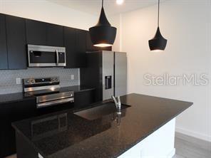 3296 Tranquil Trl, Kissimmee, FL 34747 - kitchen featuring appliances with stainless steel finishes, dark countertops, dark cabinets, and backsplash