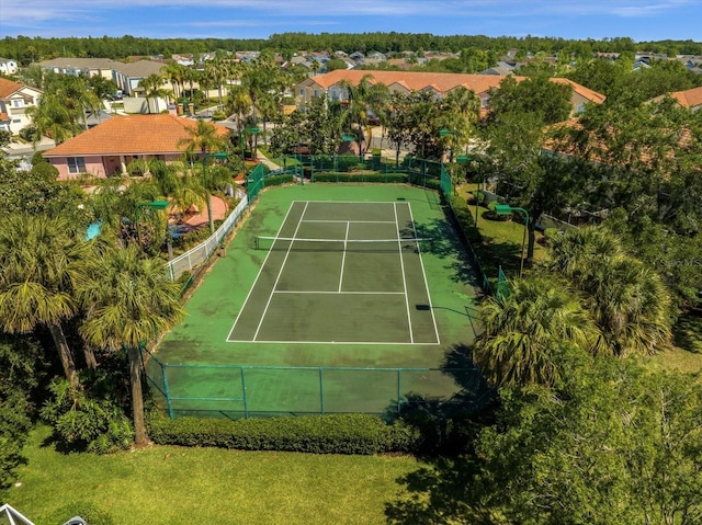view of tennis court featuring fence and a residential view