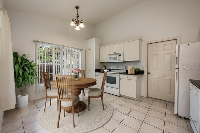39900 Bayview Dr, Lady Lake, FL 32159 - kitchen with a notable chandelier, pendant lighting, light tile patterned floors, white appliances, and dark countertops