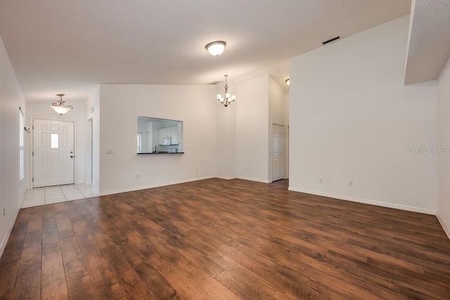 39900 Bayview Dr, Lady Lake, FL 32159 - unfurnished living room featuring baseboards, lofted ceiling, wood finished floors, and an inviting chandelier