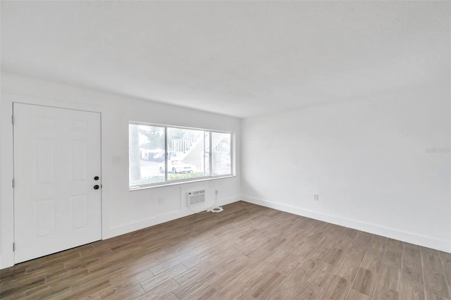 foyer featuring an AC wall unit, baseboards, and wood finished floors