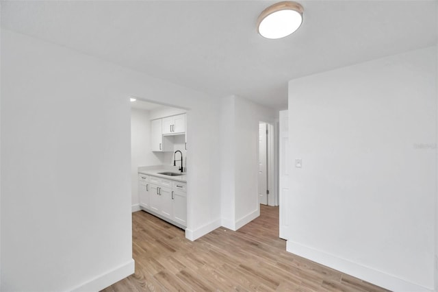 interior space featuring a sink, baseboards, and light wood-type flooring