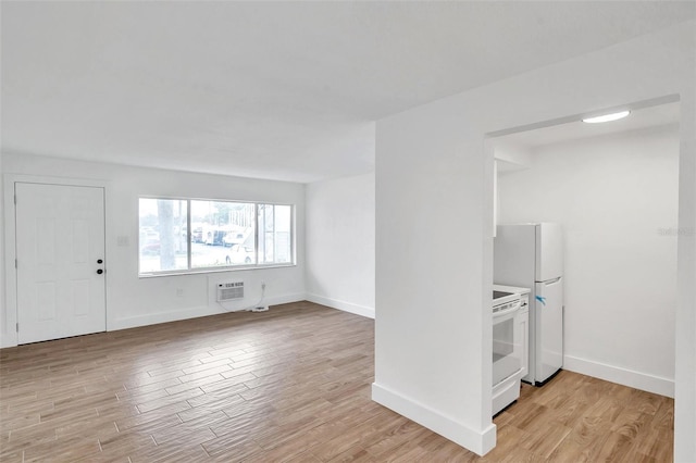 interior space with baseboards, light wood-style floors, and a wall mounted air conditioner