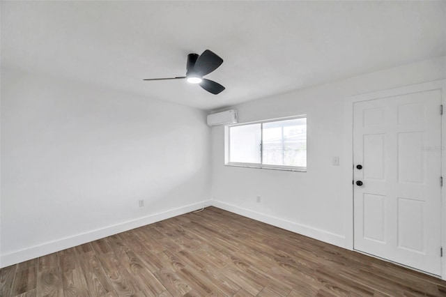 unfurnished room featuring baseboards, ceiling fan, wood finished floors, and a wall unit AC