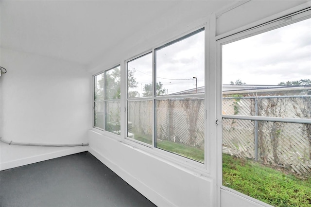 unfurnished sunroom featuring baseboards and finished concrete floors
