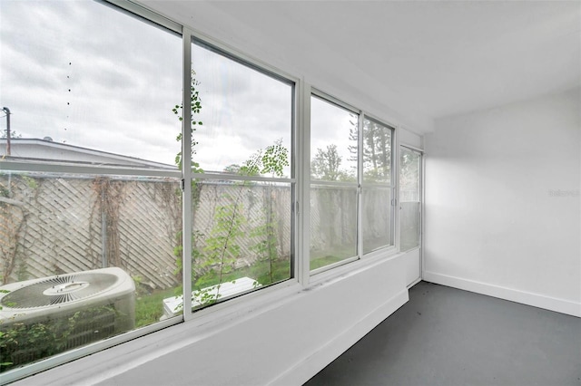 unfurnished sunroom with finished concrete flooring and baseboards