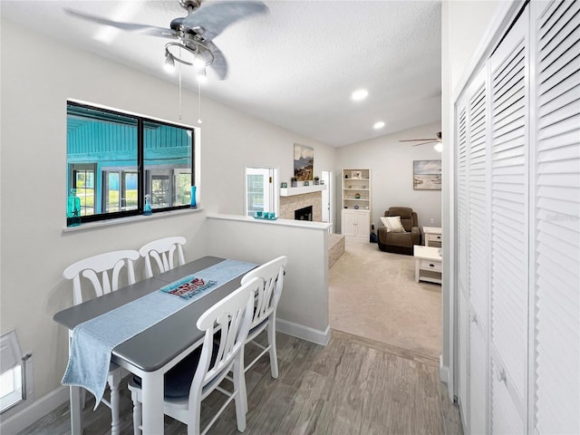 11404 Lokanotosa Trl, Orlando, FL 32817 - dining room featuring a textured ceiling, ceiling fan, wood finished floors, a fireplace, and vaulted ceiling