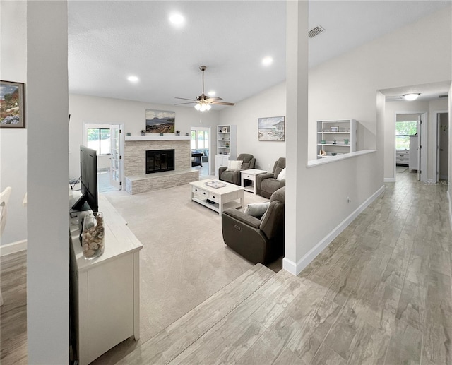 11404 Lokanotosa Trl, Orlando, FL 32817 - living room featuring a ceiling fan, a glass covered fireplace, light wood-type flooring, lofted ceiling, and visible vents