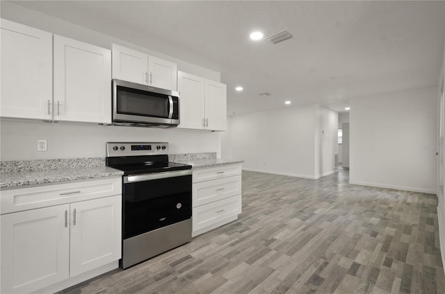 4385 Cassius St, Orlando, FL 32811 - kitchen with appliances with stainless steel finishes, recessed lighting, white cabinetry, light wood finished floors, and light stone counters