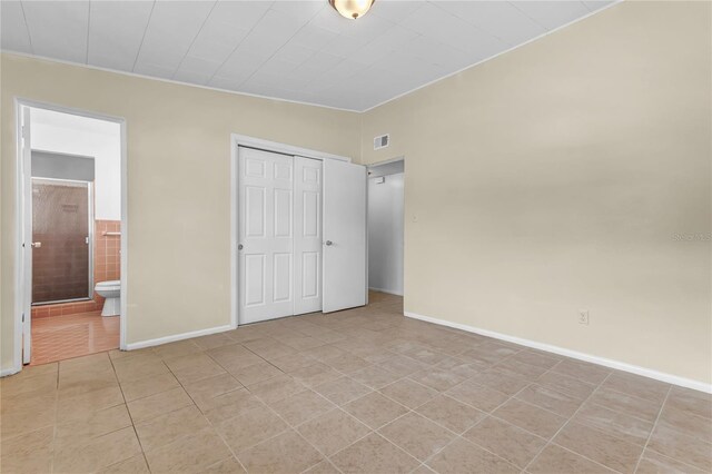 5201 Van Aken Dr, Orlando, FL 32808 - unfurnished bedroom featuring connected bathroom, a closet, light tile patterned floors, baseboards, and visible vents