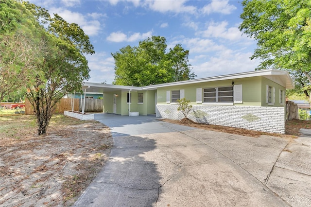 5201 Van Aken Dr, Orlando, FL 32808 - ranch-style home featuring an attached carport, brick siding, fence, and concrete driveway